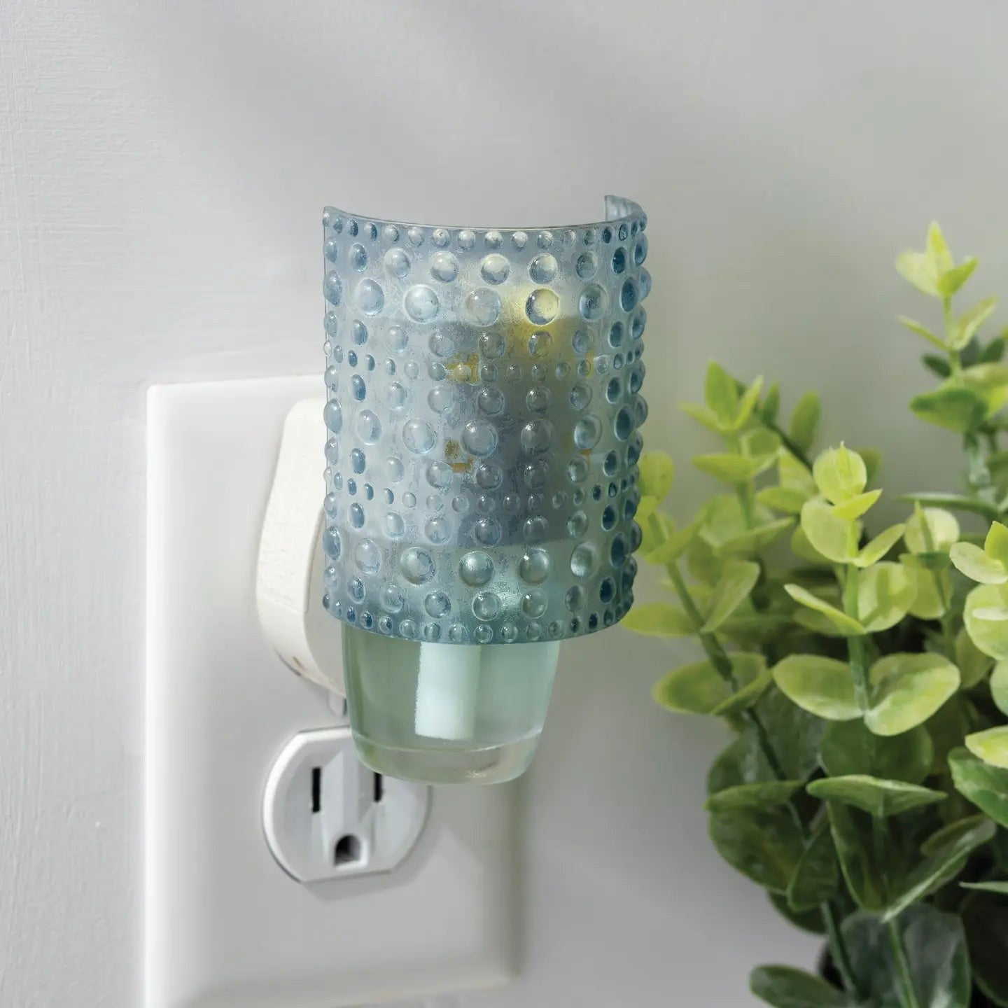 Mellow Monkey Hobnail WallScents fragrance warmer in blue glass with a textured hobnail design plugged into a wall.