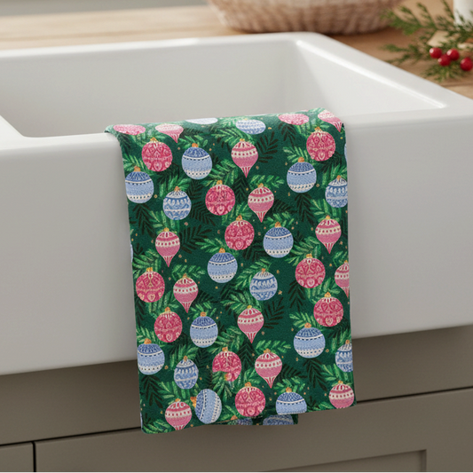 Mellow Monkey holiday bulb print waffle dish towel hanging over a white farmhouse sink in a festive kitchen