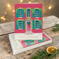 Mellow Monkey boxed holiday cards featuring a festive red brick house illustration with green wreaths and shutters.