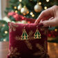 Mellow Monkey Silver Forest Stately holiday tree earrings with green enamel on a red velvet snowflake pillow.