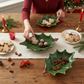Mellow Monkey hand-painted green holly leaf-shaped dolomite tray with red berries on a festive holiday table setting