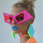 Mellow Monkey hot pink oversized cat eye sunglasses with UV400 protection worn by a model with bold makeup.