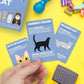 Mellow Monkey How To Speak Cat cards featuring illustrations and explanations of feline body language on blue cards.