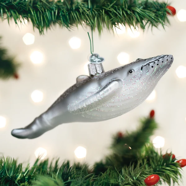 Mellow Monkey hand-blown glass humpback whale ornament in silver with glitter accents hanging on a Christmas tree