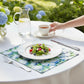 Mellow Monkey coastal hydrangea cotton dinner napkin under a white plate with salad on a round outdoor table