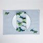 Mellow Monkey reversible woven cotton placemat featuring blue and white hydrangea artwork on a light blue background.