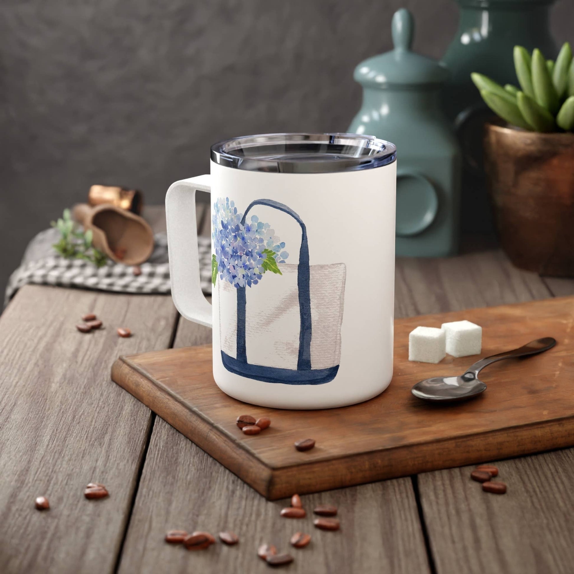 Mellow Monkey 12oz insulated stainless steel mug with a white finish and blue hydrangea tote bag illustration.