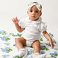 Mellow Monkey baby sitting on a soft white muslin swaddle blanket featuring a blue hydrangea floral print