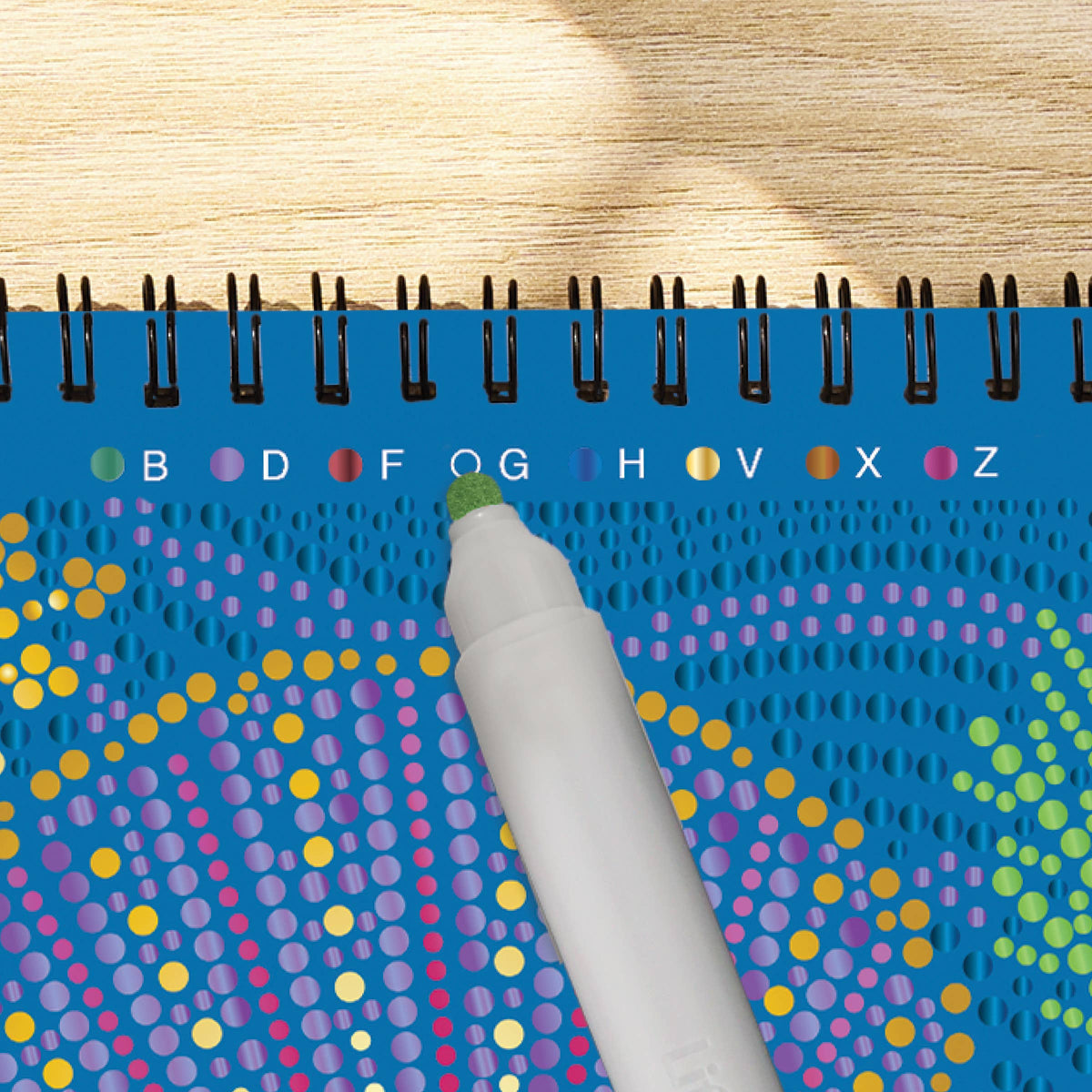 Mellow Monkey Into the Deep dot art activity book with metallic marker filling in a celestial pattern on wood table