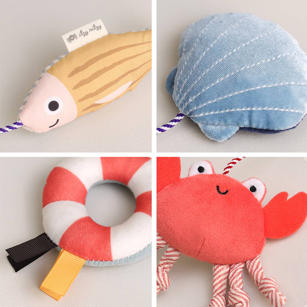 Mellow Monkey Itzy Travel Charms Seaside set featuring soft plush fish, seashell, life ring, and crab baby toys.