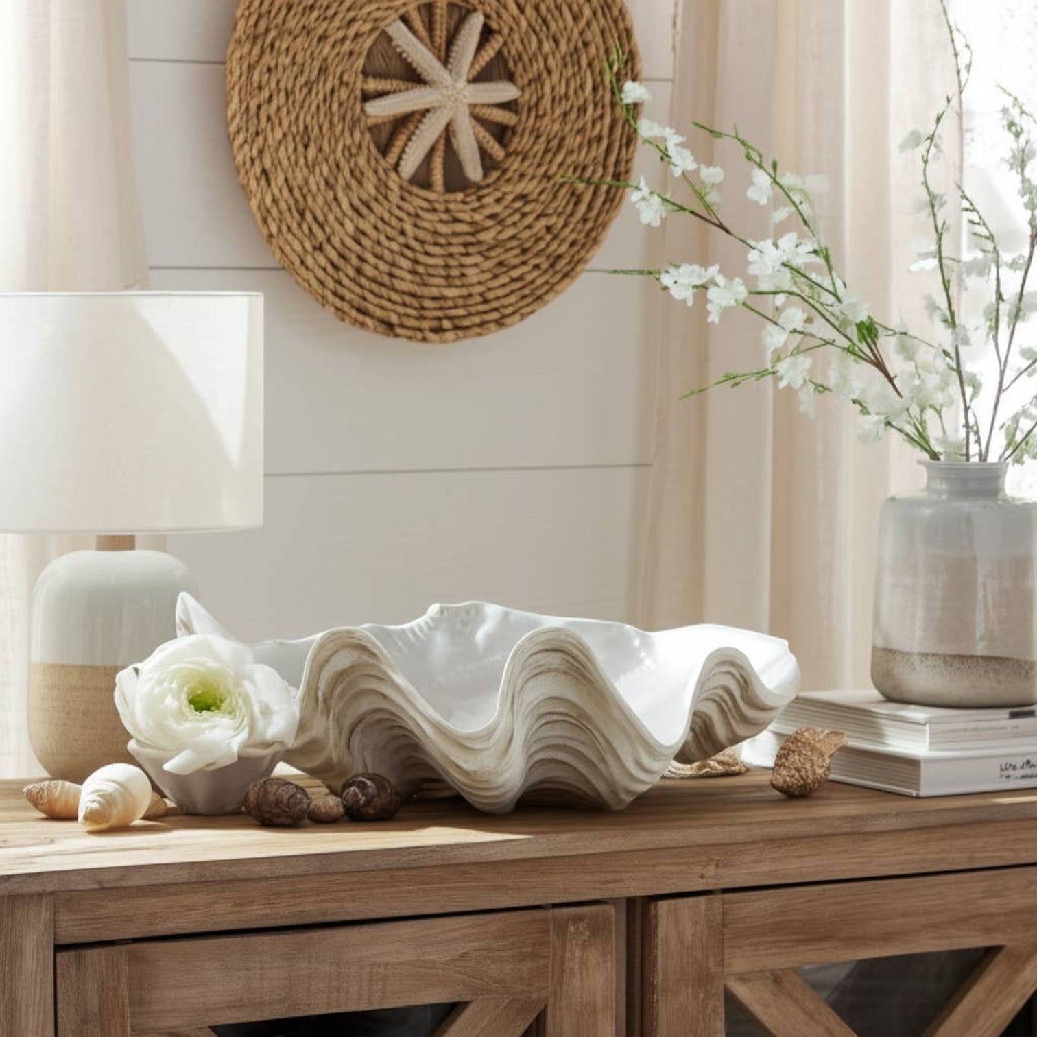 Mellow Monkey ivory resin shell-shaped decorative bowl on a wooden console table with coastal decor accents.