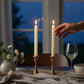 Mellow Monkey set of two 10.5-inch ivory twist taper flameless candles on a dining table with a hand reaching out