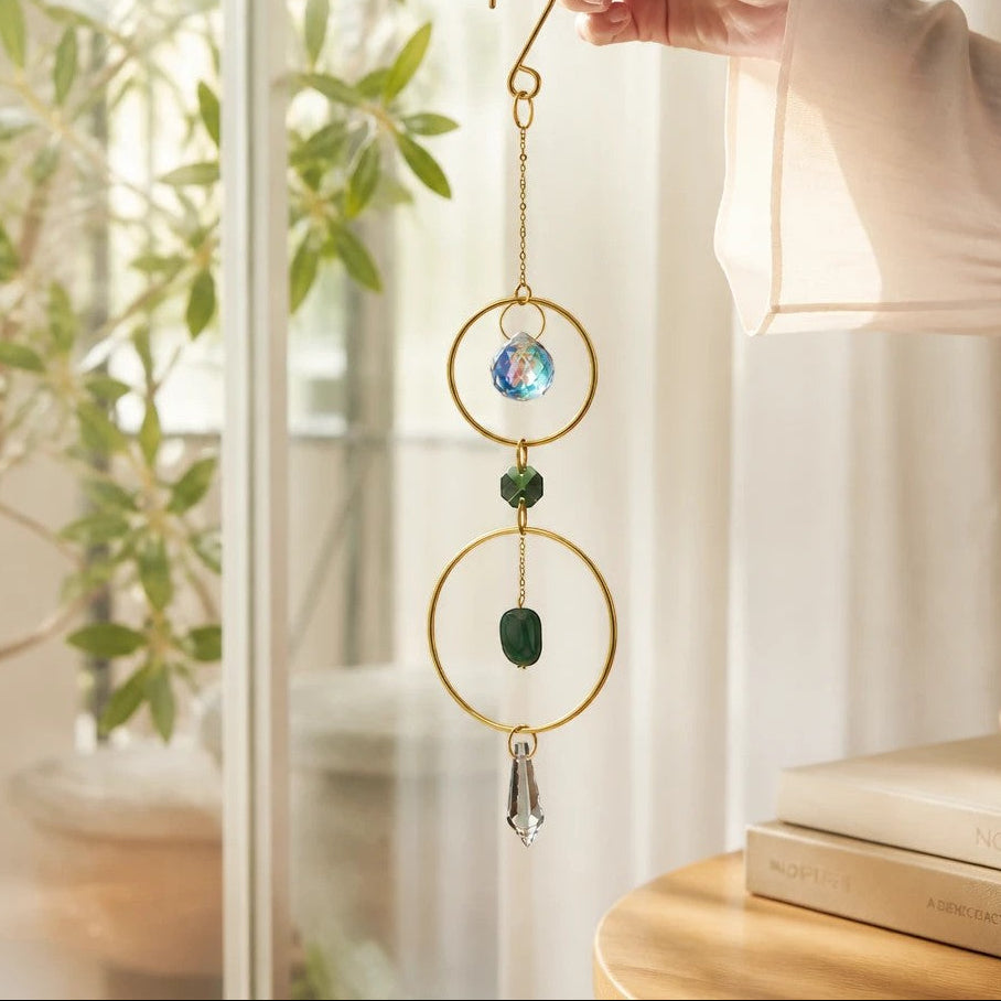 Mellow Monkey jade and crystal suncatcher with bronze rings hanging by a window to catch sunlight