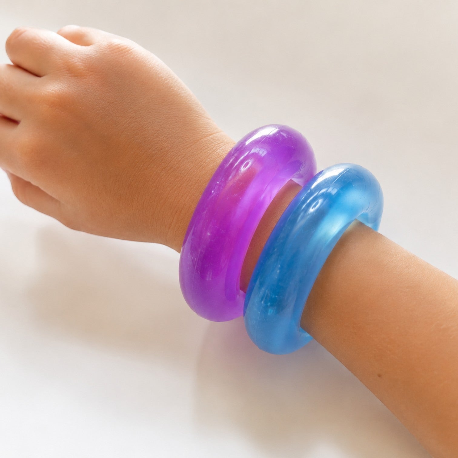 Mellow Monkey FEELZiES Jelly Donut Squishy wearable sensory fidget bracelets in translucent purple and blue on a wrist