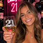 Mellow Monkey 21st birthday wine glass with jeweled number 21 held by a smiling woman at a party