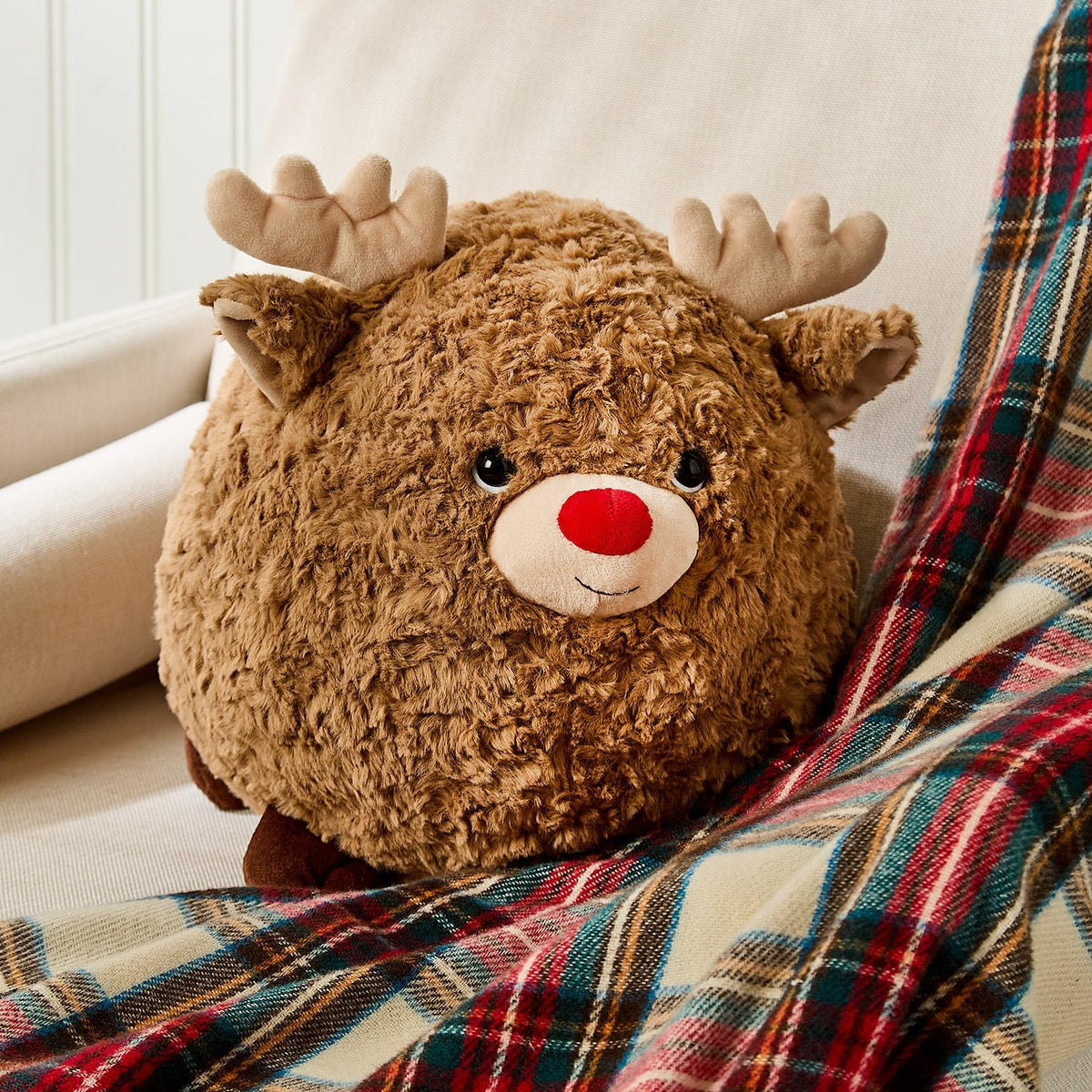 Mellow Monkey Jingle the Reindeer large round brown plush toy with a red nose and soft antlers on a plaid blanket.