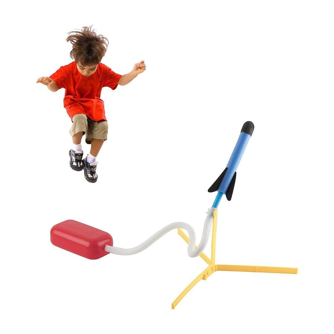 Child jumping on a Mellow Monkey foam rocket launcher set with a blue rocket and adjustable yellow tripod stand.