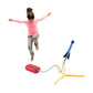 A young girl jumping on a Mellow Monkey foam rocket launcher set with a blue rocket ready for takeoff.