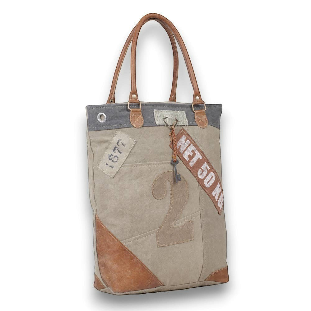 Mellow Monkey organic jute tote bag with brown leather handles, vintage-style typography, and canvas patchwork.