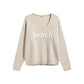 Mellow Monkey khaki lightweight cotton-blend V-neck sweater featuring a white textured BEACH graphic on the front.