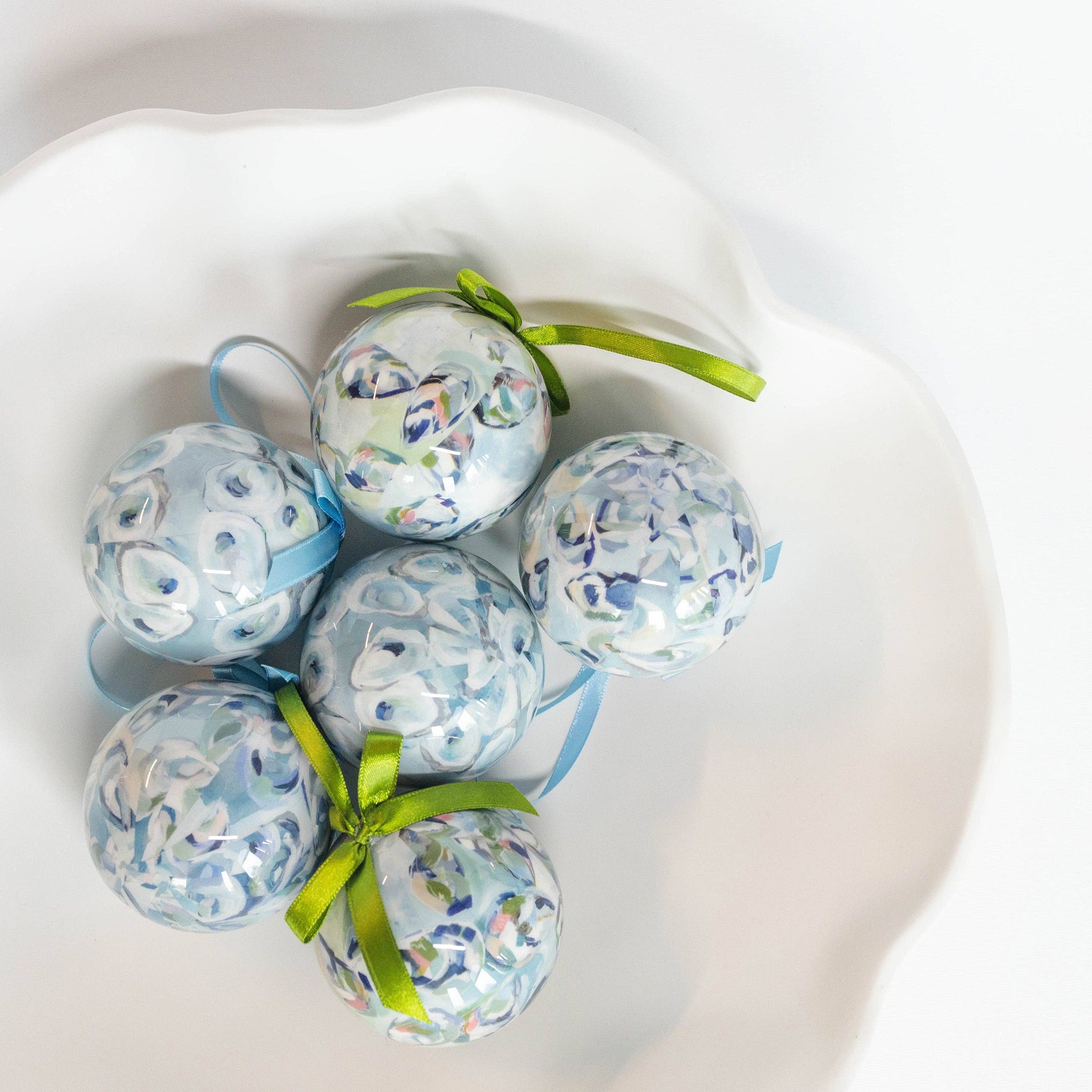 Mellow Monkey Kim Hovell shell trio decoupage ornaments with blue floral patterns and green ribbons in a white bowl