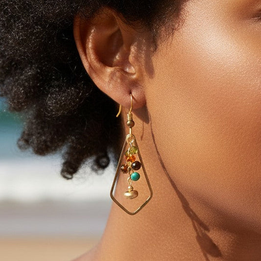 Mellow Monkey kite-shaped dangle earrings with colorful beads worn by a woman on a sunny beach.