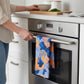 Mellow Monkey Knicks camo tea towel hanging on a stainless steel oven handle in a modern kitchen