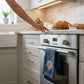 Mellow Monkey Knicks floral tea towel hanging on a stainless steel oven handle in a modern kitchen
