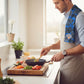 Mellow Monkey Knicks floral tea towel draped over a man's shoulder while cooking in a bright kitchen