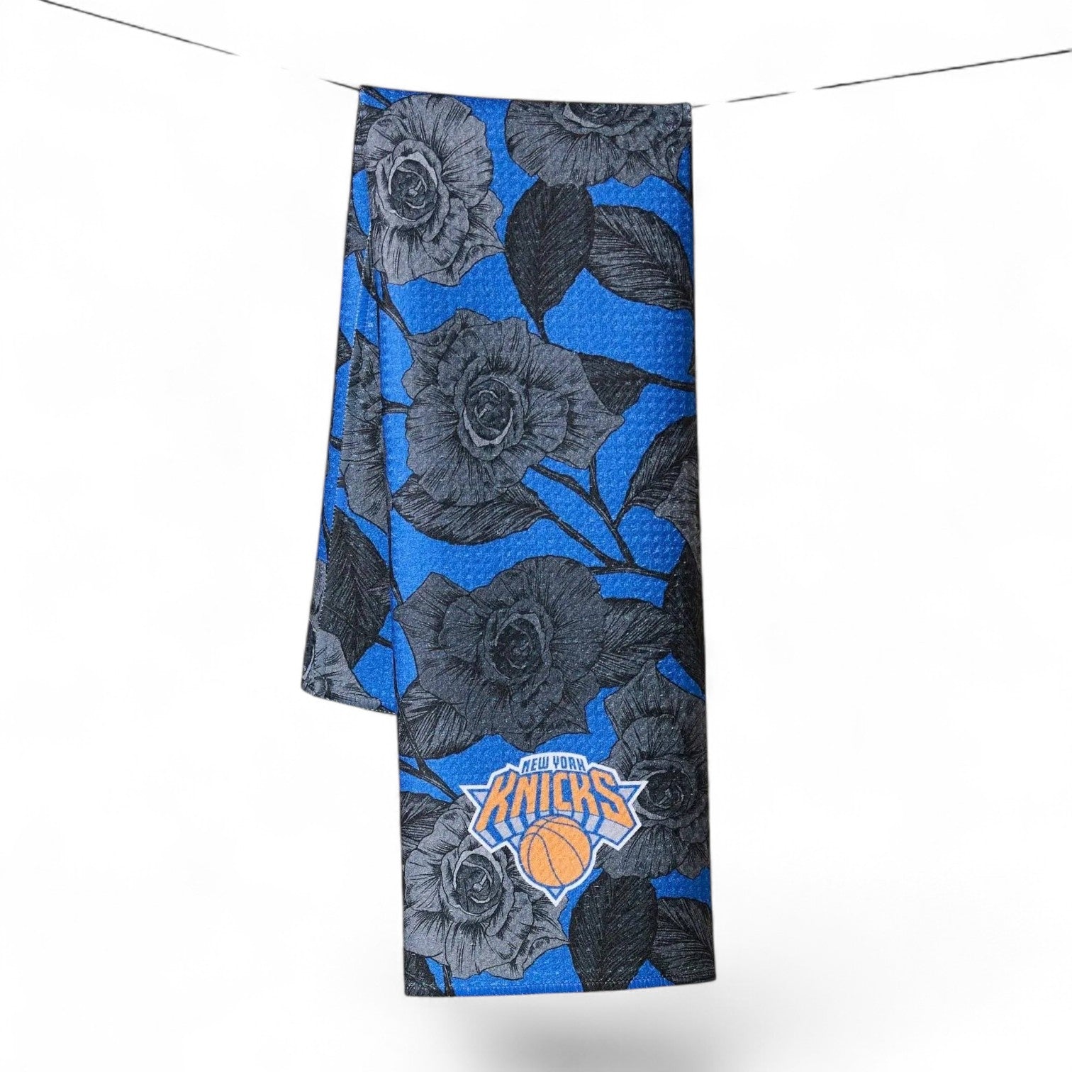 Mellow Monkey Knicks floral tea towel in blue and black with NBA team logo, hanging on a line.
