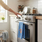 Mellow Monkey Knicks Grip tea towel hanging on a stainless steel oven handle in a bright, modern kitchen.