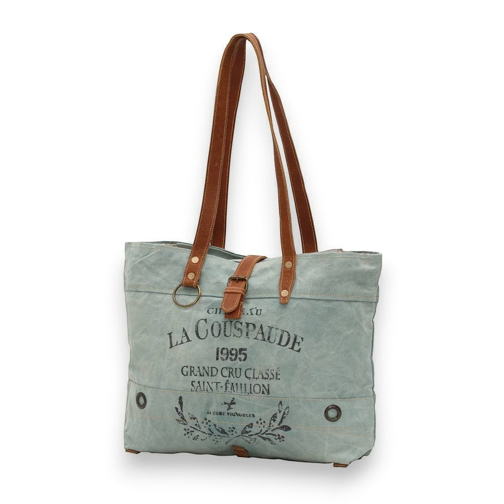 Mellow Monkey La Couspaude canvas tote bag in sage green with brown leather handles and vintage-style graphic print.