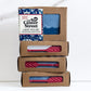 Mellow Monkey Lake House handmade bar soap, blue with white wave design, in kraft box with nautical print.