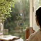 Mellow Monkey Lapiz healing ornament suncatcher with blue crystals and bronze rings hanging in a sunlit window