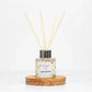 Mellow Monkey Pet House Lavender Green Tea reed diffuser in a glass bottle with wooden reeds on a round wood base.
