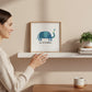Mellow Monkey Lead with Kindness framed art print featuring a blue elephant holding a flower. Wood frame, 8-3/4 x 8-3/4-in.