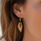 Mellow Monkey leaf-shaped earrings with textured center worn by a woman on a beach