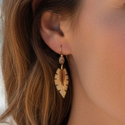 Mellow Monkey leaf-shaped earrings with textured center worn by a woman on a beach