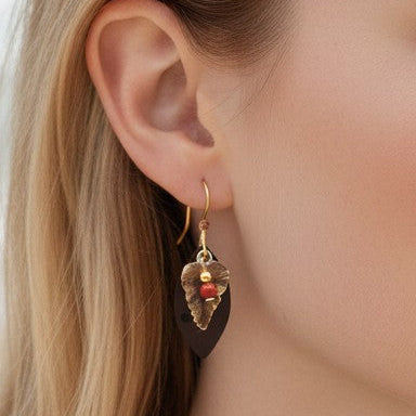 Mellow Monkey Leaf On Warm Oval With Ball earrings featuring a nature-inspired design on a woman at the beach.