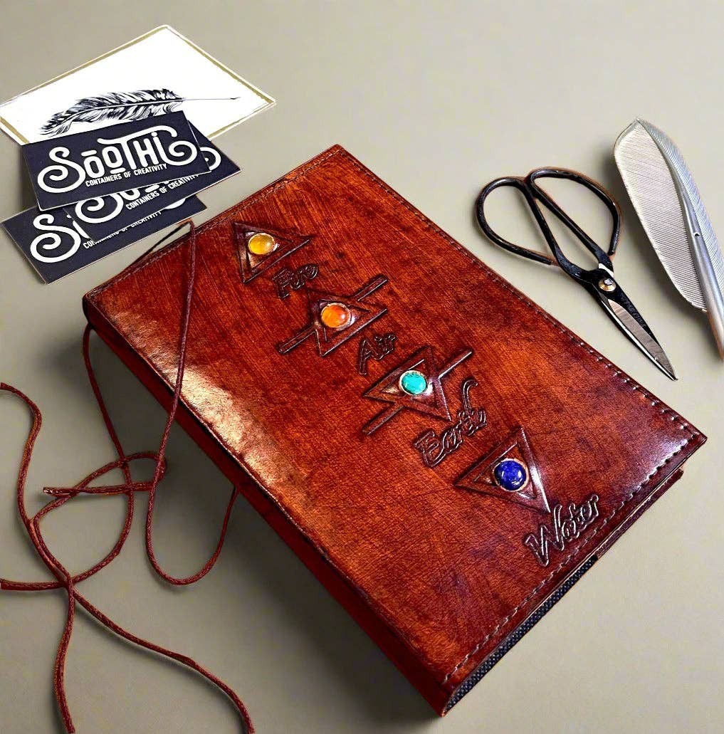 Mellow Monkey reddish-brown leather journal with embossed elemental symbols and gemstone accents, cord closure.