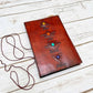 Mellow Monkey reddish-brown leather journal with embossed elemental symbols and gemstone accents, featuring a cord closure.