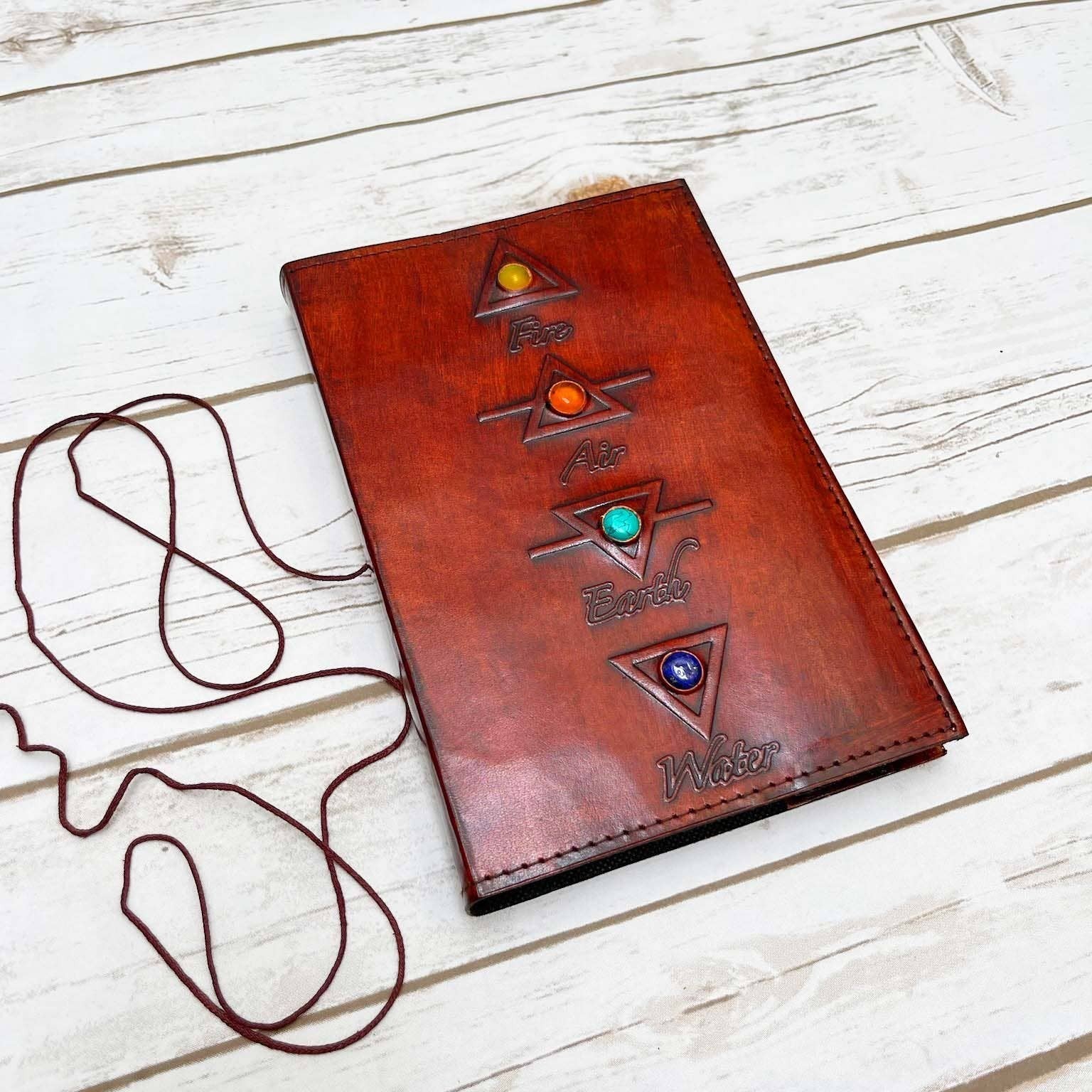 Mellow Monkey reddish-brown leather journal with embossed elemental symbols and gemstone accents, featuring a cord closure.