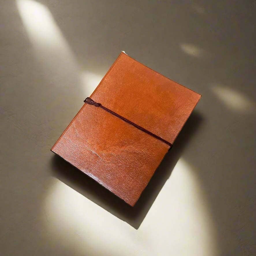 Mellow Monkey tan leather journal with unlined pages and elastic closure. Hand-stitched, 8x6 inches.