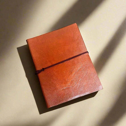 Mellow Monkey hand-stitched tan leather journal with unlined pages and elastic closure. Geometric debossed corners.