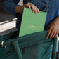 Mellow Monkey Lifelines Cozy Cottage Dot-by-Letter art pad being placed into a green bag by a person in a denim jacket.