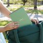 Mellow Monkey Lifelines FlowArt trace-to-doodle pad with a sage green cover being placed into a dark green tote bag.