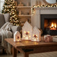 Mellow Monkey lighted porcelain holiday houses with festive wreaths on a wooden table in a cozy living room setting