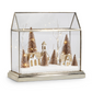 Mellow Monkey lighted snowy village terrarium with miniature gold houses and bottle brush trees in a glass house case.