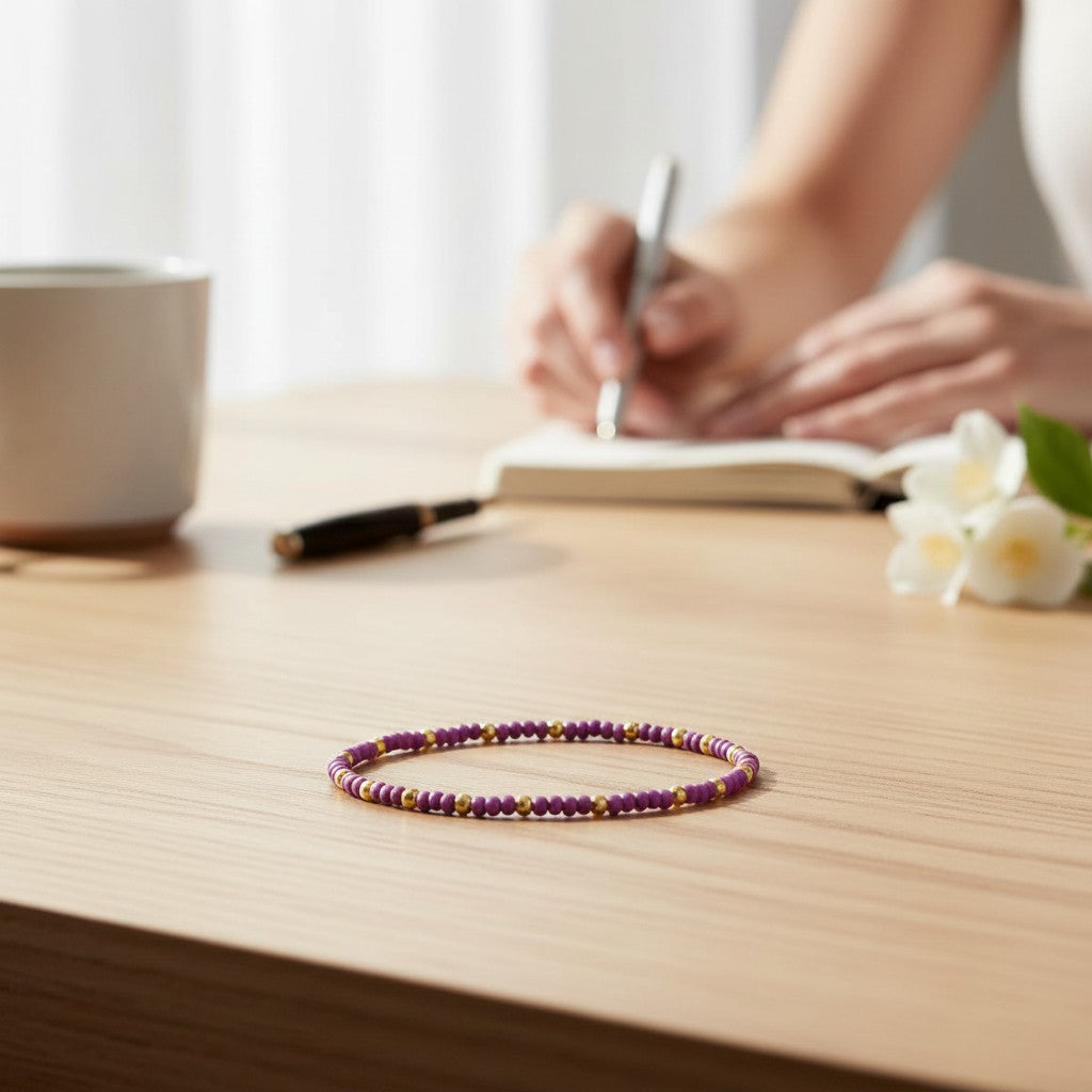 Mellow Monkey lilac seed bead bracelet with 18K gold plated brass accents resting on a wooden desk.