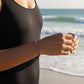 Mellow Monkey lilac seed bead stretch bracelet with 18K gold plated accents worn by a woman on a sunny beach.